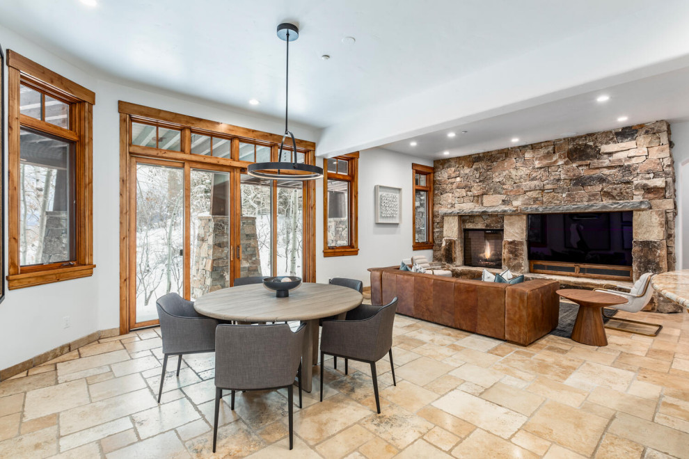 Photo of a mid-sized country open concept family room in Salt Lake City with a game room, multi-coloured walls, limestone floors, a standard fireplace, a stone fireplace surround, a wall-mounted tv and beige floor.