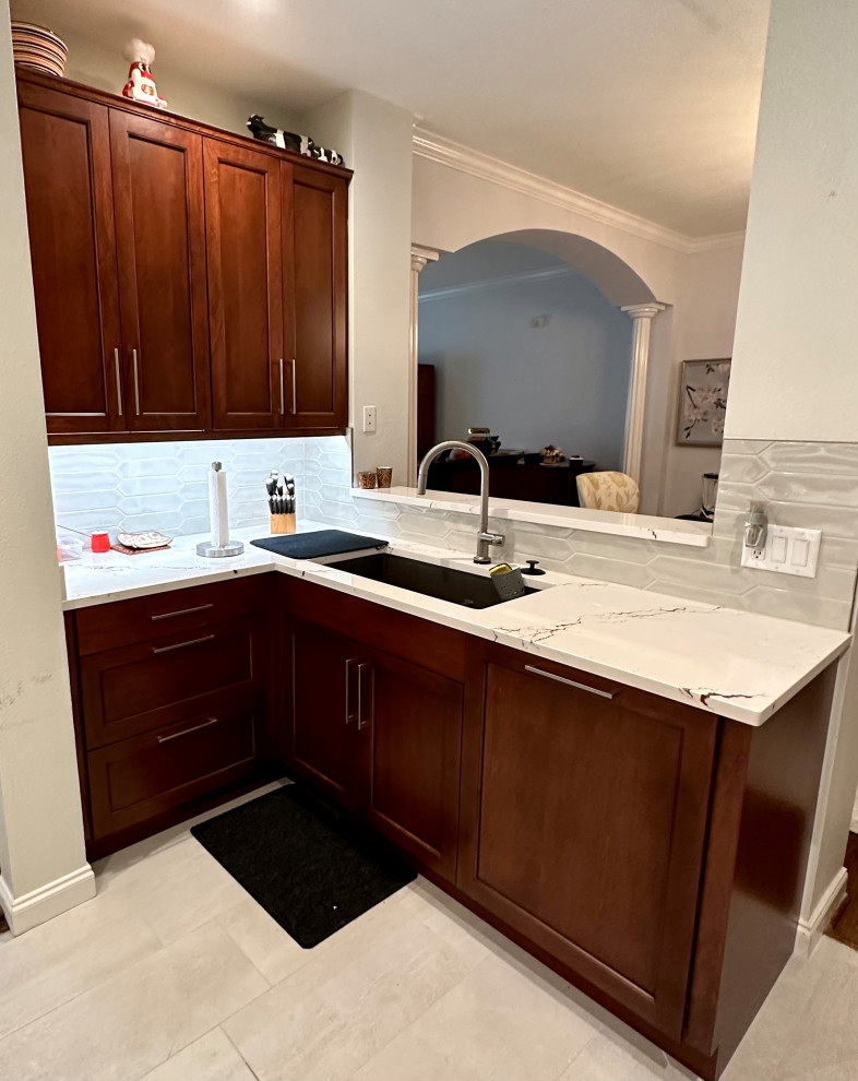 Inspiration for a small transitional u-shaped porcelain tile and beige floor enclosed kitchen remodel in Houston with an undermount sink, recessed-panel cabinets, medium tone wood cabinets, quartz countertops, white backsplash, ceramic backsplash, stainless steel appliances, no island and multicolored countertops