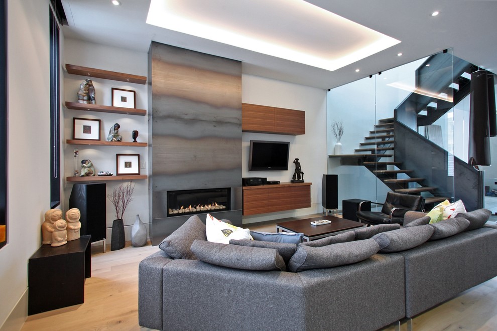 This is an example of a contemporary open concept family room in Toronto with light hardwood floors, a ribbon fireplace, a metal fireplace surround and a wall-mounted tv.