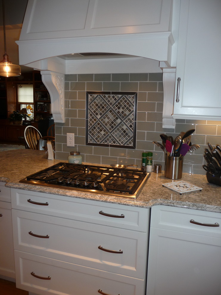 U-shaped light wood floor enclosed kitchen photo in Milwaukee with an undermount sink, glass tile backsplash and stainless steel appliances