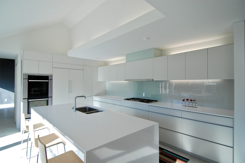 Design ideas for a modern galley eat-in kitchen in Kansas City with a double-bowl sink, white cabinets, quartz benchtops, white splashback, glass sheet splashback, panelled appliances, porcelain floors and with island.