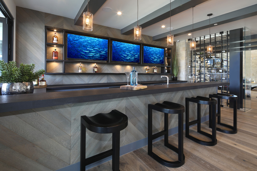 Inspiration for a transitional galley wet bar in Orange County with open cabinets, black cabinets, grey splashback, timber splashback, medium hardwood floors and brown floor.