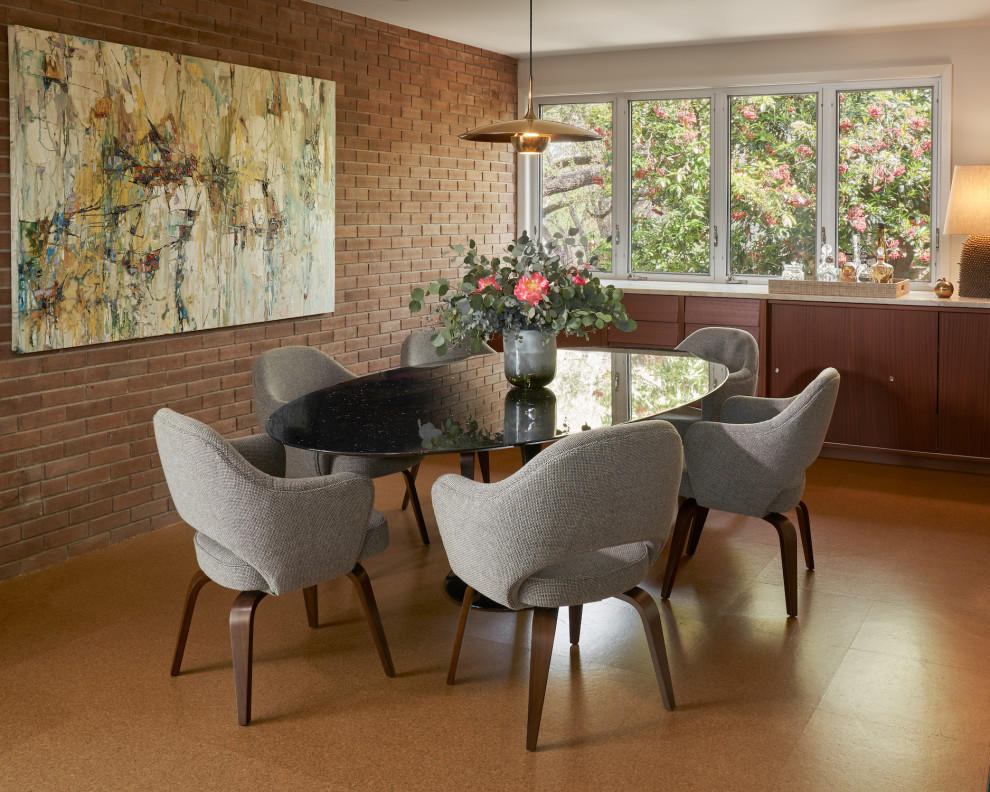 Mid-sized midcentury dining room in Austin with cork floors, brown floor, brown walls and brick walls.