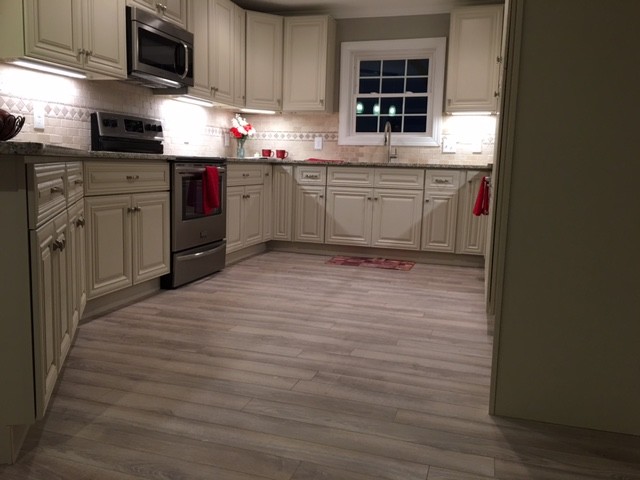 Photo of a mid-sized arts and crafts u-shaped separate kitchen in Charlotte with raised-panel cabinets, white cabinets, granite benchtops, beige splashback, stone tile splashback, stainless steel appliances, light hardwood floors and no island.