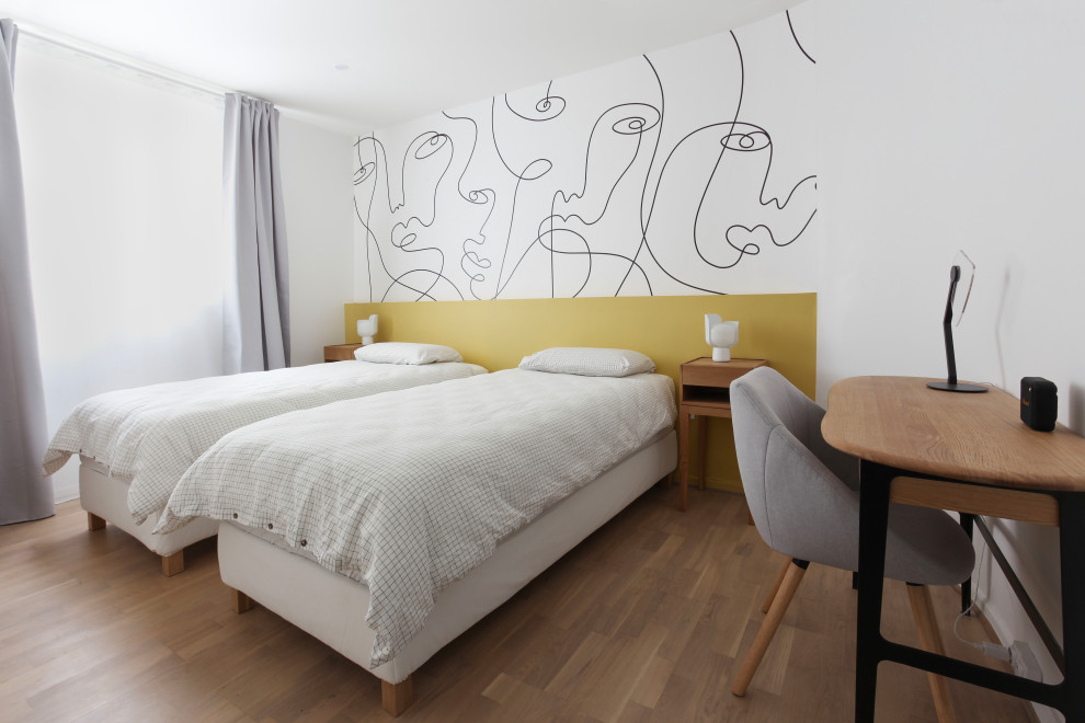 Modelo de habitación de invitados actual de tamaño medio sin chimenea con paredes amarillas, suelo laminado y papel pintado
