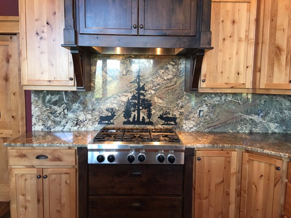 Example of a large mountain style l-shaped dark wood floor and brown floor eat-in kitchen design in Portland with a farmhouse sink, shaker cabinets, light wood cabinets, granite countertops, stone slab backsplash, stainless steel appliances and an island