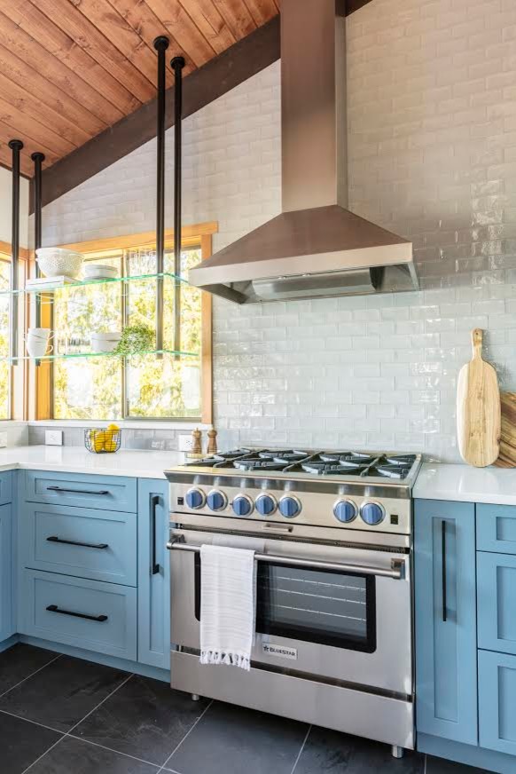 Inspiration for a large modern u-shaped kitchen in Seattle with a farmhouse sink, shaker cabinets, blue cabinets, quartzite benchtops, white splashback, subway tile splashback, stainless steel appliances, slate floors, a peninsula, black floor and white benchtop.