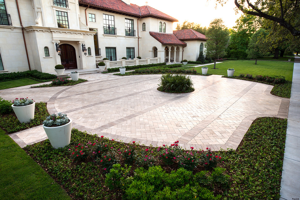 Inspiration for a mediterranean front yard driveway in Dallas with natural stone pavers.