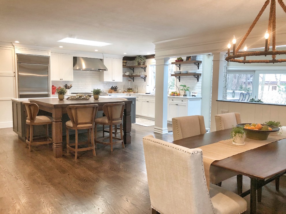 Inspiration for a huge transitional dark wood floor and brown floor eat-in kitchen remodel with an undermount sink, shaker cabinets, white cabinets, quartz countertops, white backsplash, porcelain backsplash, stainless steel appliances, an island and white countertops