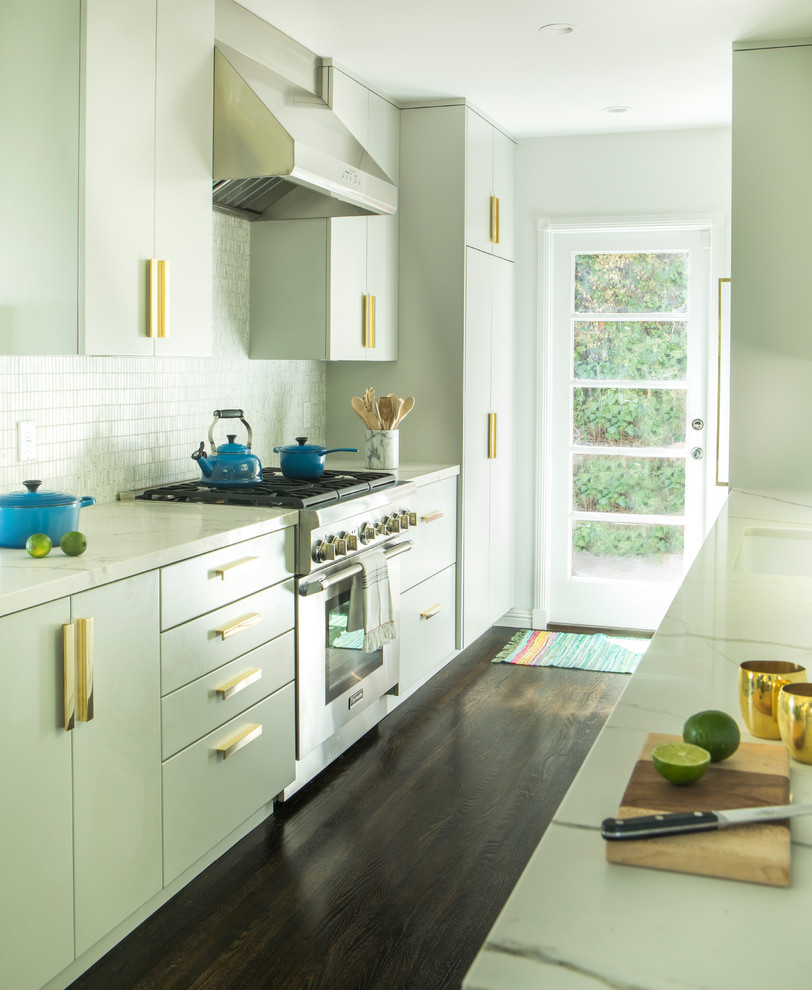 Inspiration for a transitional galley kitchen in Los Angeles with flat-panel cabinets, green cabinets, white splashback, mosaic tile splashback, stainless steel appliances, dark hardwood floors, no island and brown floor.