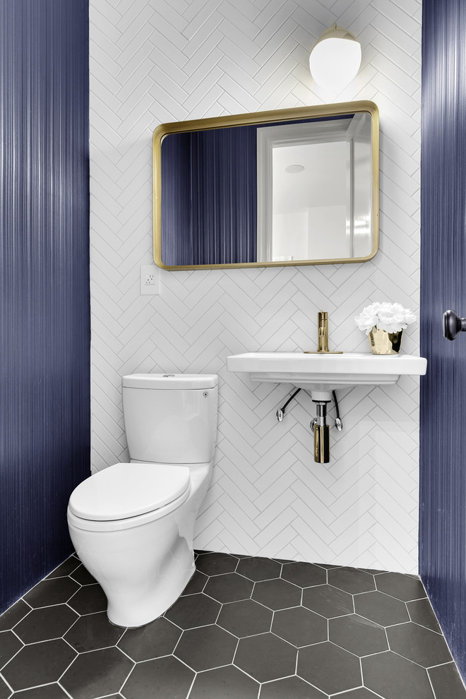 Transitional powder room in New York with a two-piece toilet, white tile, blue walls, a wall-mount sink and grey floor.