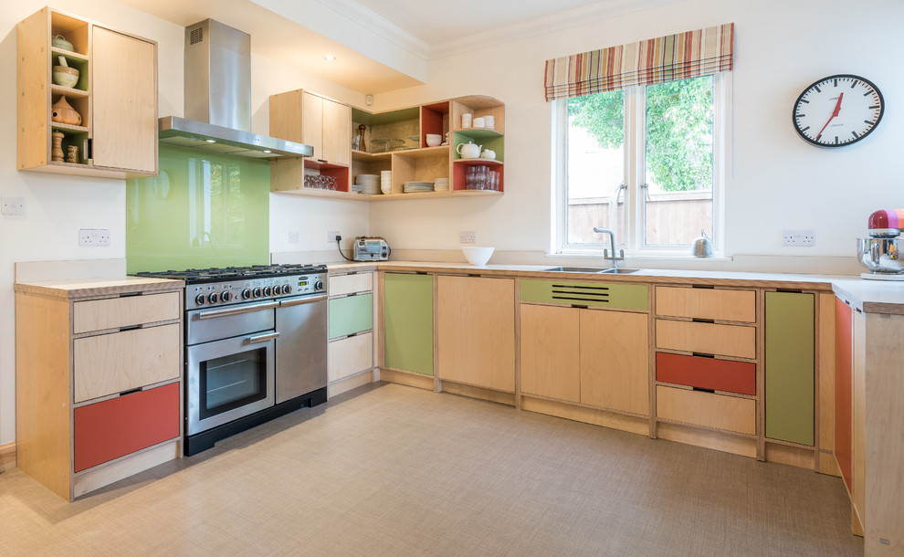 Design ideas for a mid-sized midcentury u-shaped open plan kitchen in Other with a double-bowl sink, light wood cabinets, wood benchtops, green splashback, glass sheet splashback, stainless steel appliances, flat-panel cabinets, a peninsula, beige floor and beige benchtop.