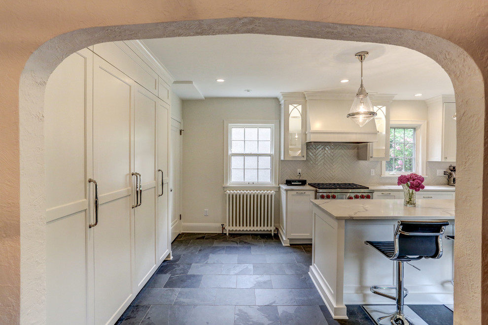 Example of a mid-sized transitional u-shaped slate floor and gray floor enclosed kitchen design in Minneapolis with a farmhouse sink, recessed-panel cabinets, white cabinets, quartz countertops, white backsplash, ceramic backsplash, stainless steel appliances, an island and white countertops