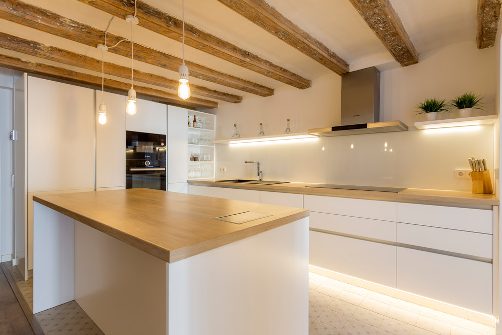 Inspiration for a large scandinavian u-shaped open plan kitchen in Barcelona with a single-bowl sink, white cabinets, wood benchtops, white splashback, glass sheet splashback, black appliances, ceramic floors, with island and multi-coloured floor.