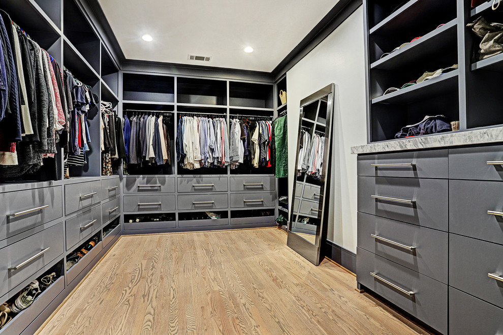 Design ideas for a large transitional gender-neutral walk-in wardrobe in Houston with flat-panel cabinets, grey cabinets, light hardwood floors and brown floor.