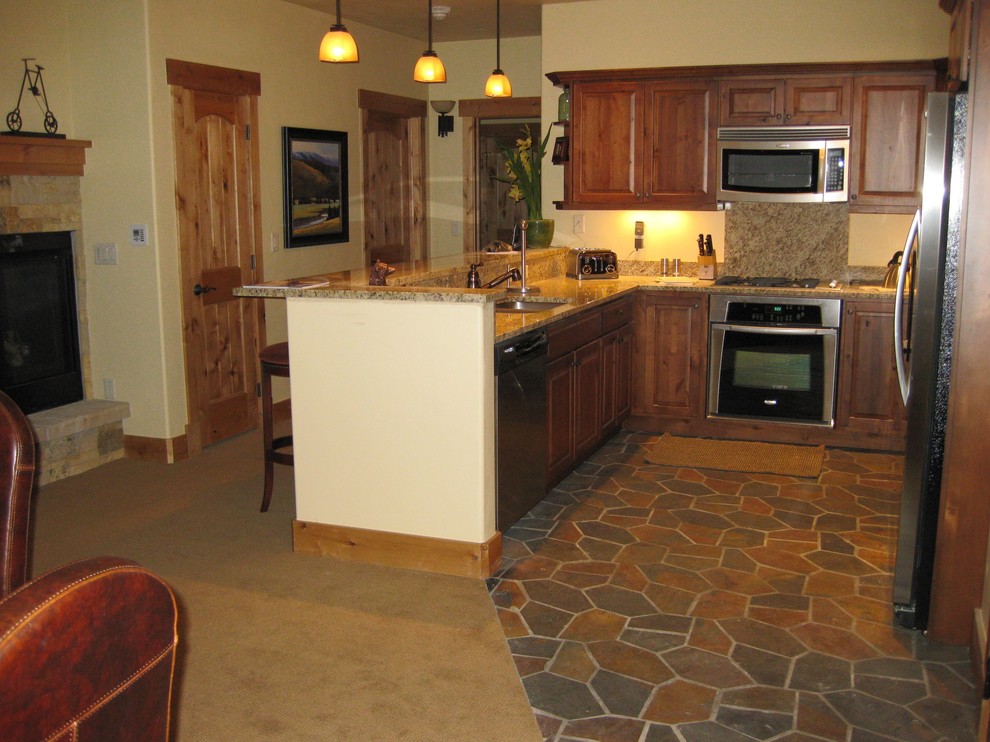 Open concept kitchen - mid-sized rustic l-shaped terra-cotta tile open concept kitchen idea with a double-bowl sink, raised-panel cabinets, dark wood cabinets, granite countertops, white appliances, beige backsplash, stone tile backsplash and a peninsula