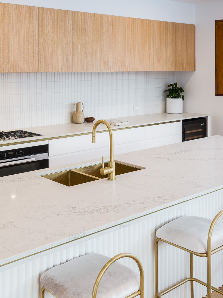 Imagen de cocina contemporánea grande con salpicadero blanco, electrodomésticos de acero inoxidable, suelo de madera en tonos medios y península