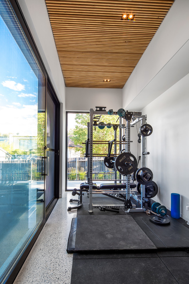 This is an example of a small contemporary home gym in Other with white walls, concrete floors and white floor.