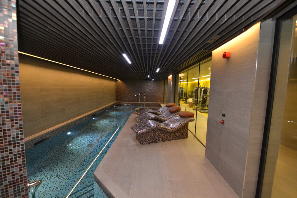 Photo of a mid-sized contemporary indoor pool in London with a pool house.