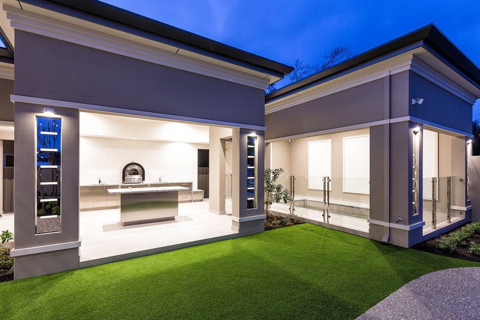 Réalisation d'une très grande terrasse arrière design avec une cuisine d'été, un gravier de granite et une extension de toiture.