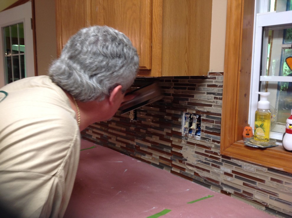 L-shaped eat-in kitchen photo with an undermount sink, flat-panel cabinets, brown backsplash, glass tile backsplash, stainless steel appliances and a peninsula