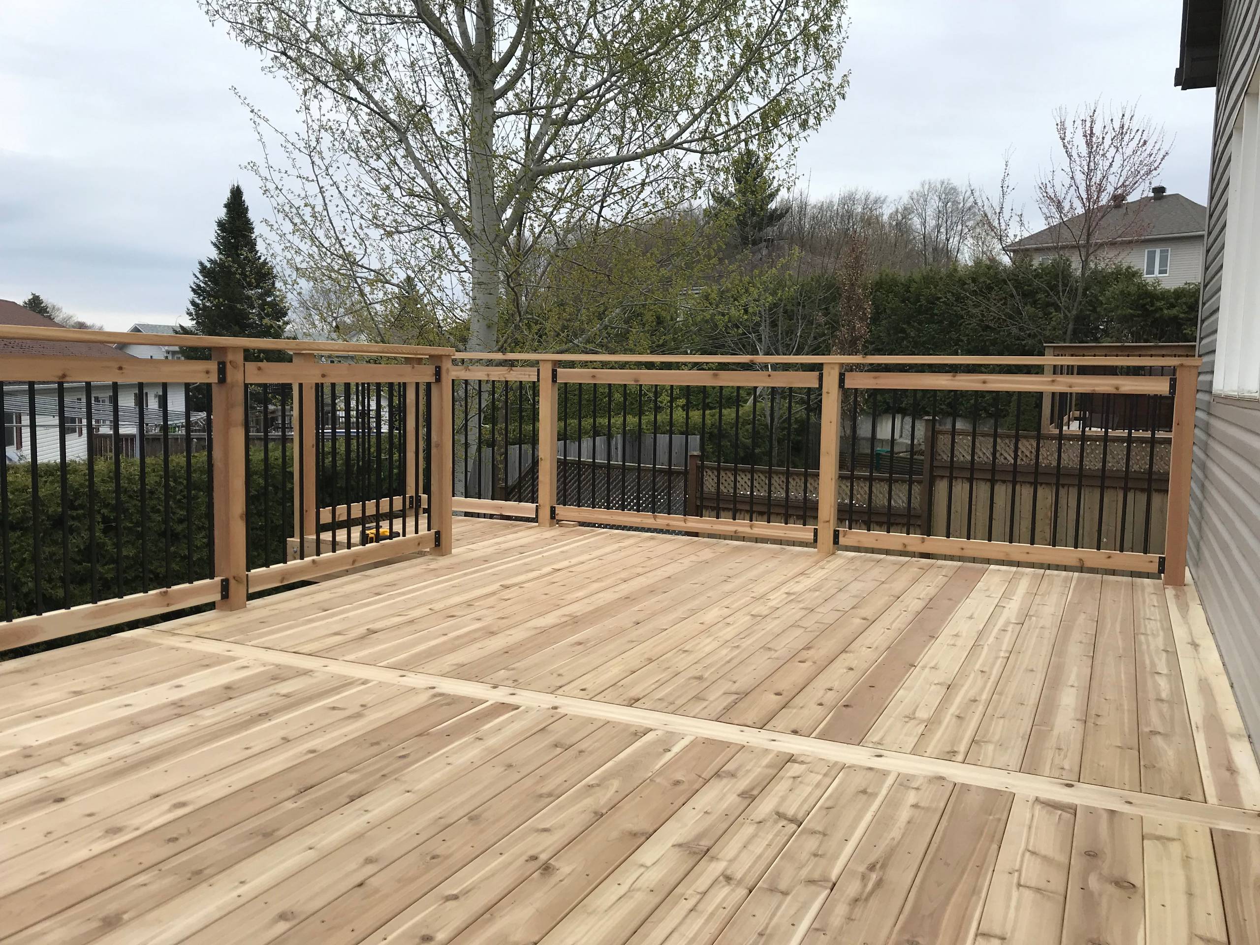 Walk-out red cedar deck with black round spindles
