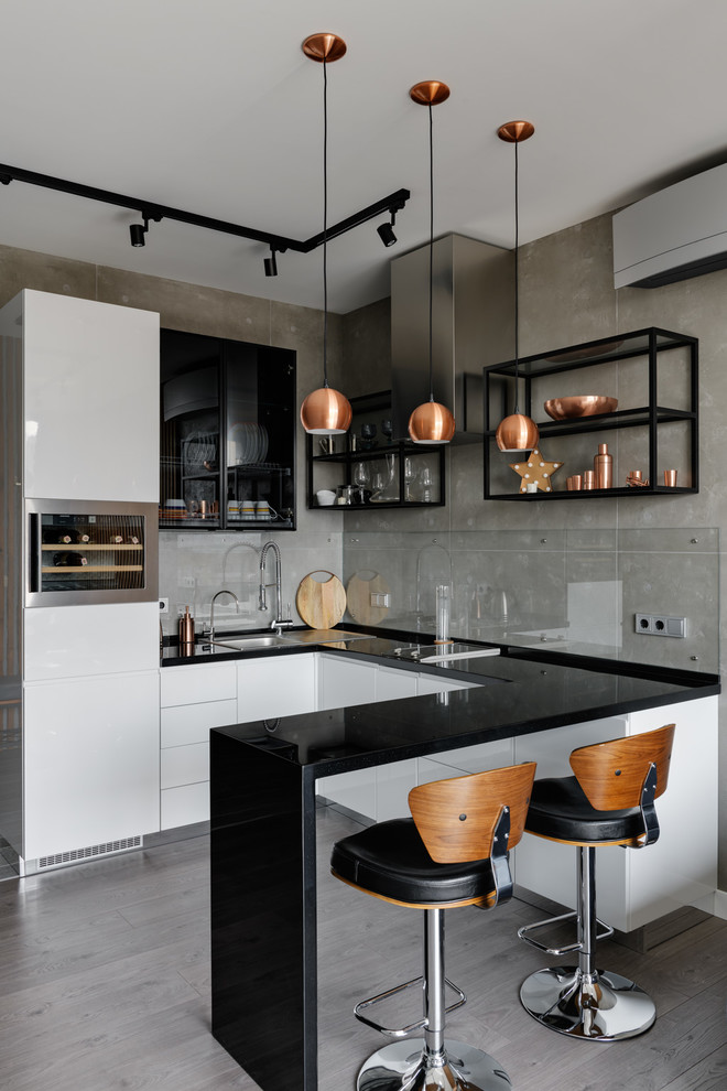 Photo of a mid-sized contemporary u-shaped open plan kitchen with a drop-in sink, flat-panel cabinets, white cabinets, quartz benchtops, stainless steel appliances, laminate floors, grey floor, black benchtop and a peninsula.