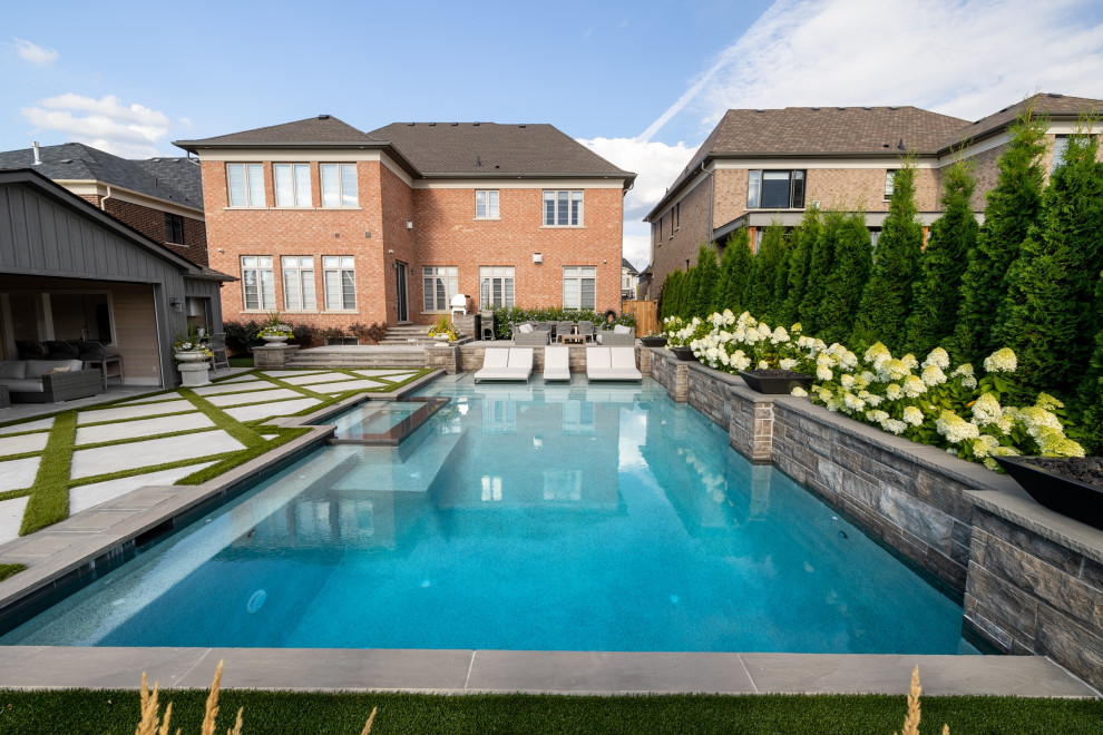 Cette image montre un grand piscine avec aménagement paysager arrière traditionnel rectangle avec une dalle de béton.