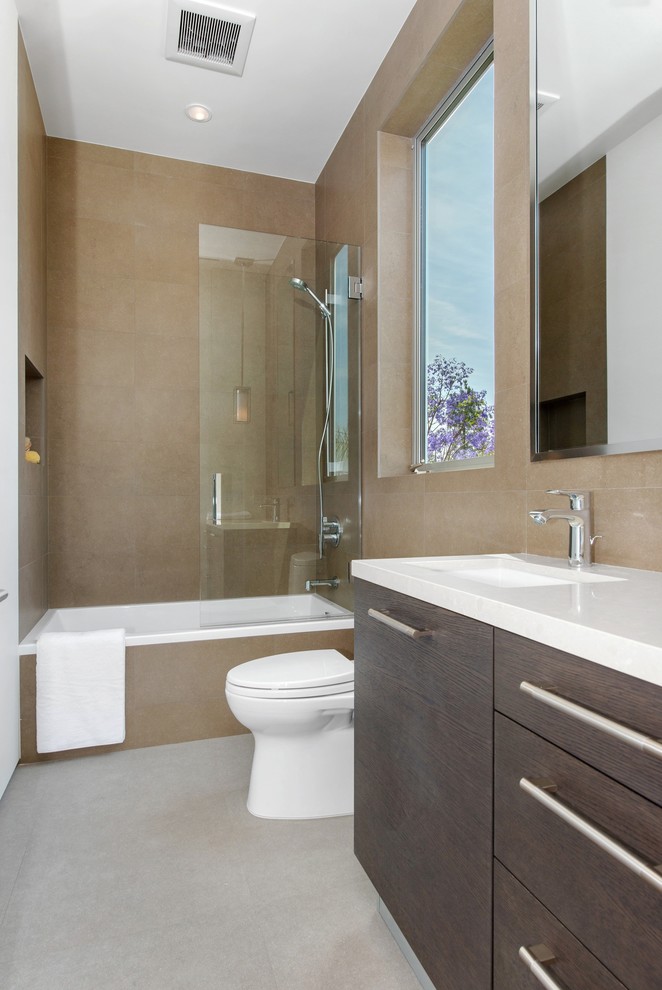 Photo of a mid-sized modern master bathroom in Los Angeles with flat-panel cabinets, dark wood cabinets, a drop-in tub, a shower/bathtub combo, an integrated sink, a one-piece toilet, white tile, ceramic tile, beige walls, cement tiles, solid surface benchtops, grey floor and an open shower.