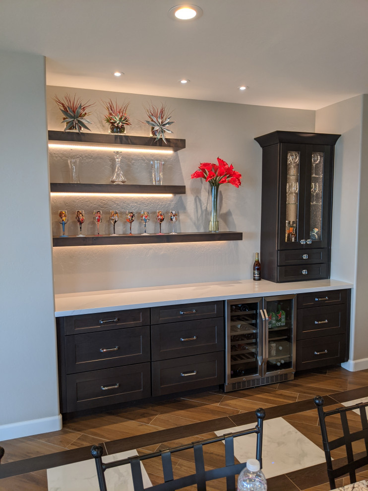 Inspiration for a single-wall home bar in Phoenix with shaker cabinets, dark wood cabinets, quartzite benchtops, porcelain floors, brown floor and white benchtop.