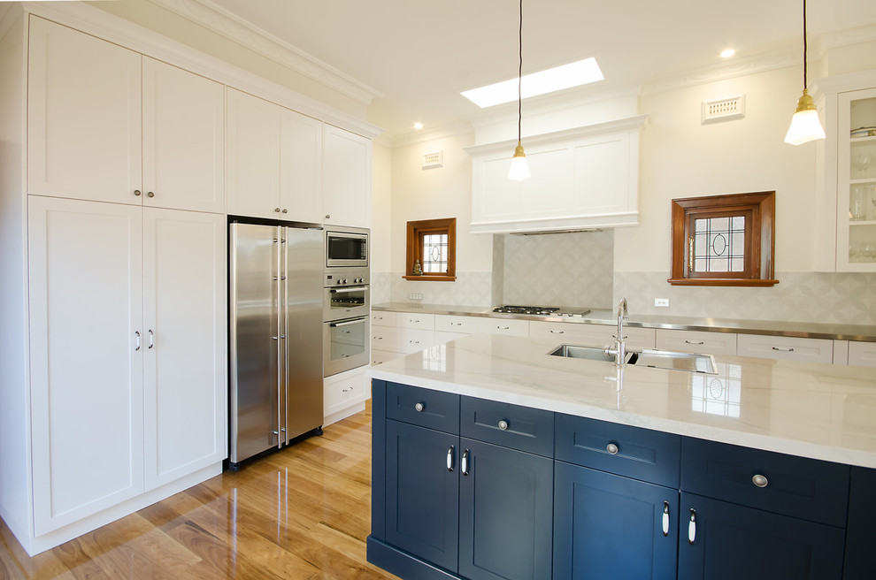This is an example of a large traditional l-shaped eat-in kitchen in Melbourne with an undermount sink, shaker cabinets, black cabinets, granite benchtops, grey splashback, ceramic splashback, stainless steel appliances, medium hardwood floors and with island.