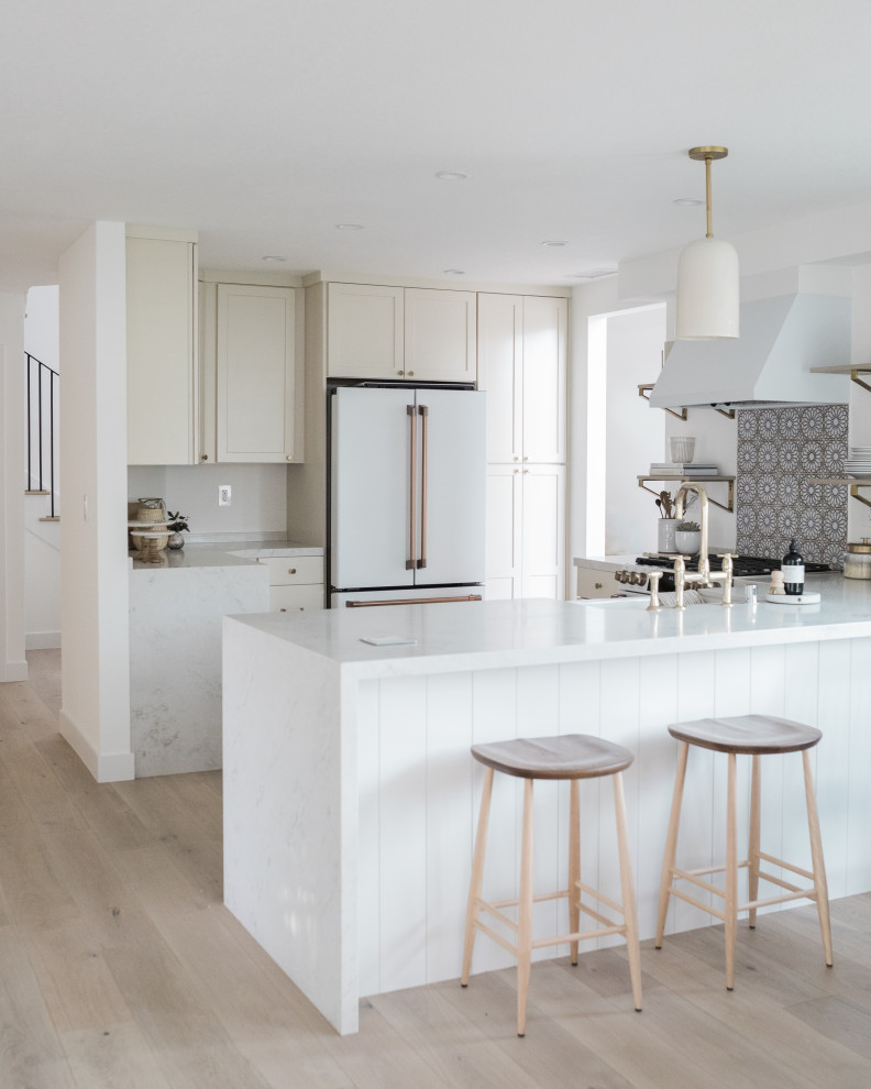 Small coastal l-shaped kitchen in Orange County with shaker cabinets, white cabinets, an island and white worktops.