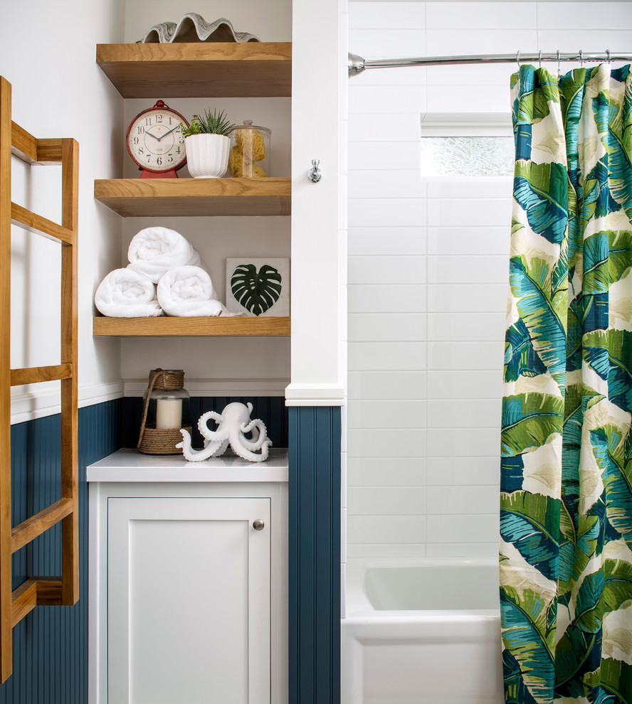 Photo of a mid-sized beach style kids bathroom in San Francisco with furniture-like cabinets, white cabinets, an alcove tub, a shower/bathtub combo, porcelain tile, blue walls and grey floor.