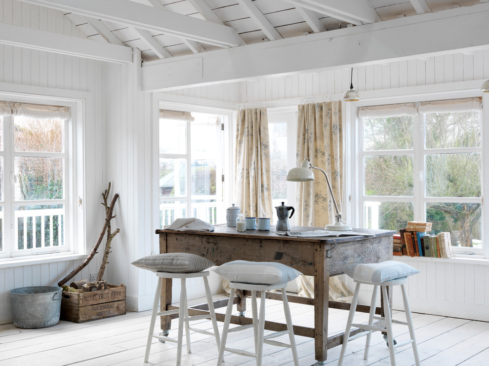 Photo of a beach style dining room in Sussex with white walls and light hardwood floors.