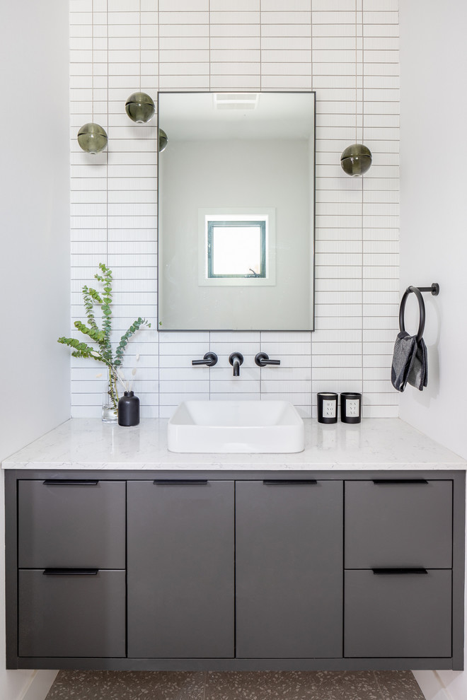 Inspiration for a scandinavian powder room in Vancouver with flat-panel cabinets, grey cabinets, white tile, white walls, a vessel sink and white benchtops.