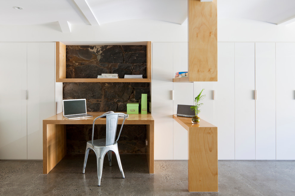 Inspiration for a mid-sized scandinavian study room in Melbourne with white walls, concrete floors and a built-in desk.