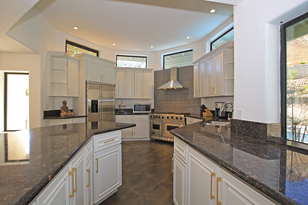 Large transitional u-shaped porcelain tile and brown floor eat-in kitchen photo with an undermount sink, shaker cabinets, white cabinets, granite countertops, black backsplash, stainless steel appliances, an island, black countertops and ceramic backsplash