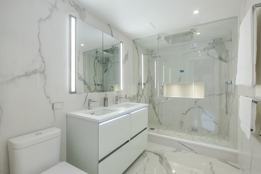 Design ideas for an expansive contemporary master wet room bathroom in New York with glass-front cabinets, white cabinets, a one-piece toilet, white tile, stone slab, white walls, marble floors, a wall-mount sink, quartzite benchtops and white floor.