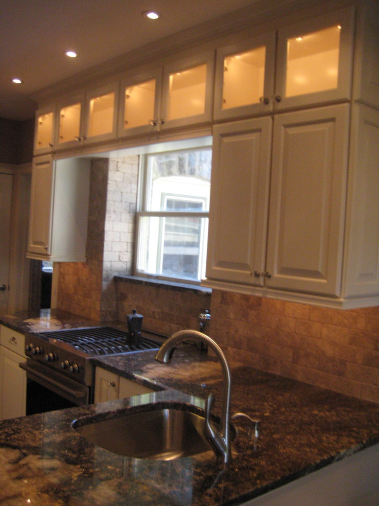 Transitional l-shaped eat-in kitchen photo in Philadelphia with a single-bowl sink, raised-panel cabinets, white cabinets, granite countertops, brown backsplash, stone tile backsplash and stainless steel appliances