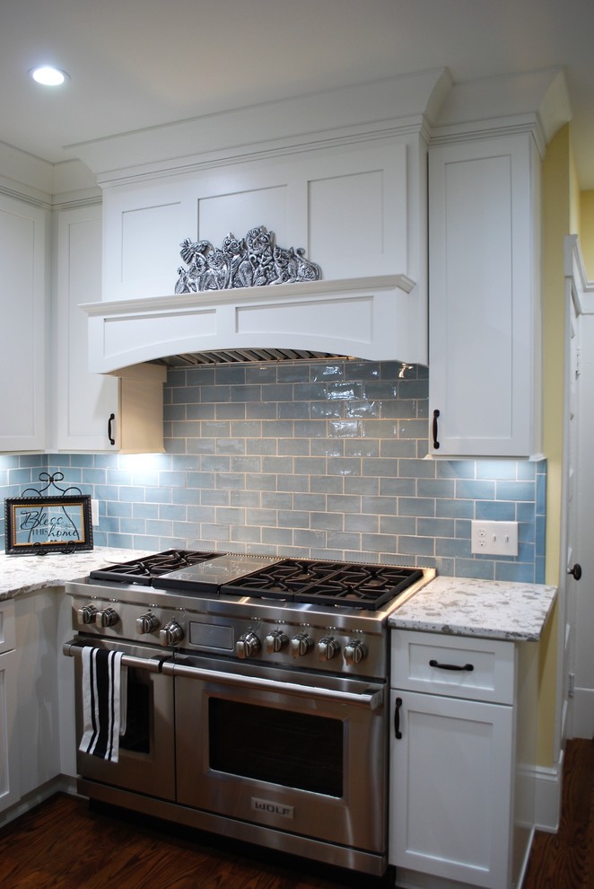 Photo of a mid-sized traditional kitchen in Cleveland with a farmhouse sink, shaker cabinets, white cabinets, quartz benchtops, blue splashback, ceramic splashback, stainless steel appliances, light hardwood floors, with island and white benchtop.