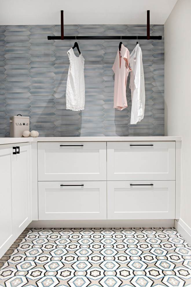 Inspiration for a mid-sized contemporary l-shaped dedicated laundry room remodel in Toronto with shaker cabinets, white cabinets, quartz countertops, blue backsplash, ceramic backsplash and white countertops
