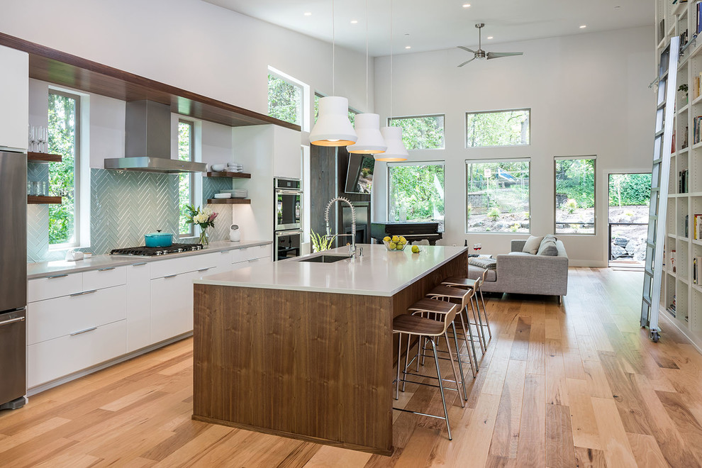 Inspiration for a large modern galley open plan kitchen in Other with an undermount sink, flat-panel cabinets, white cabinets, quartz benchtops, blue splashback, glass tile splashback, stainless steel appliances, light hardwood floors, with island and beige floor.
