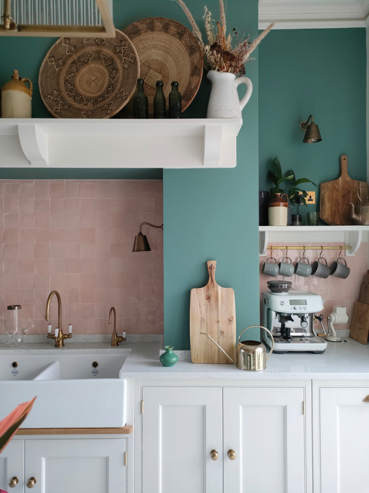 Inspiration for a mid-sized arts and crafts single-wall eat-in kitchen in Other with a farmhouse sink, shaker cabinets, white cabinets, granite benchtops, pink splashback, porcelain splashback, black appliances, marble floors, with island, white floor and pink benchtop.