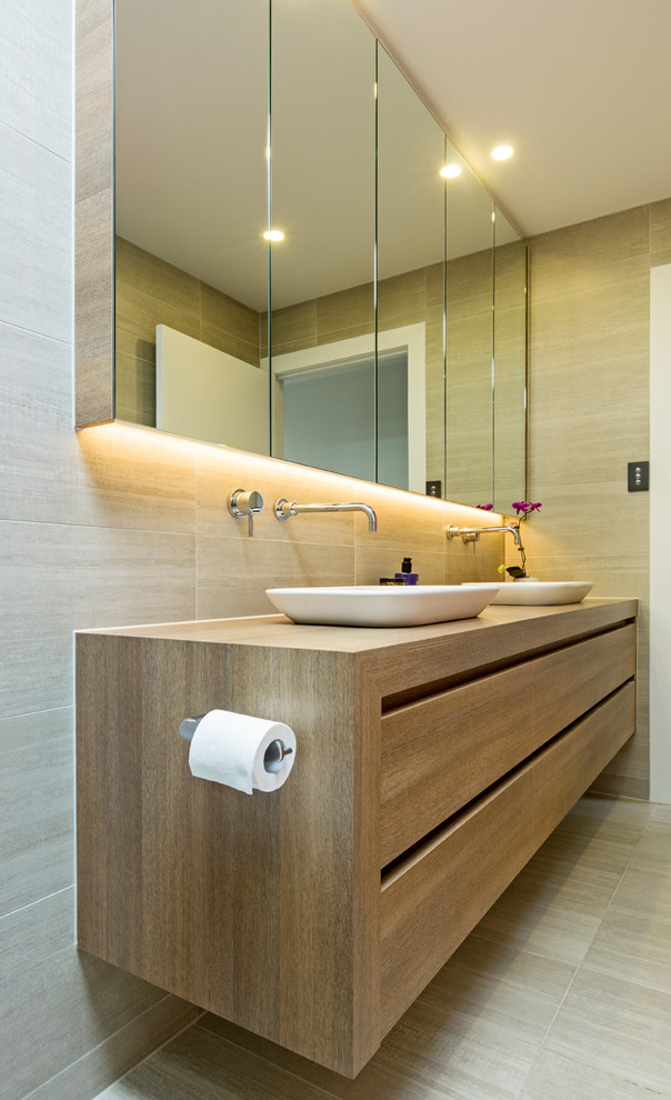 Design ideas for a mid-sized contemporary master bathroom in Melbourne with furniture-like cabinets, light wood cabinets, beige tile, stone slab, beige walls, cement tiles, a vessel sink, wood benchtops and beige floor.