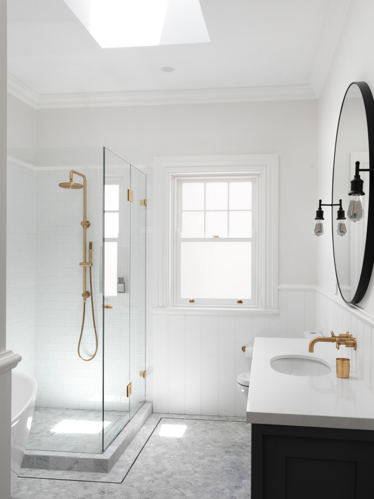 Design ideas for a large transitional master bathroom in Sydney with shaker cabinets, grey cabinets, a freestanding tub, a corner shower, a two-piece toilet, white tile, white walls, marble floors, an undermount sink, engineered quartz benchtops, grey floor, a hinged shower door and white benchtops.