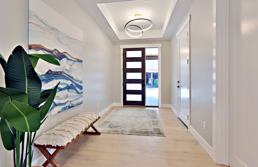 This is an example of a mid-sized contemporary foyer in Seattle with white walls, light hardwood floors, a single front door, a dark wood front door and recessed.