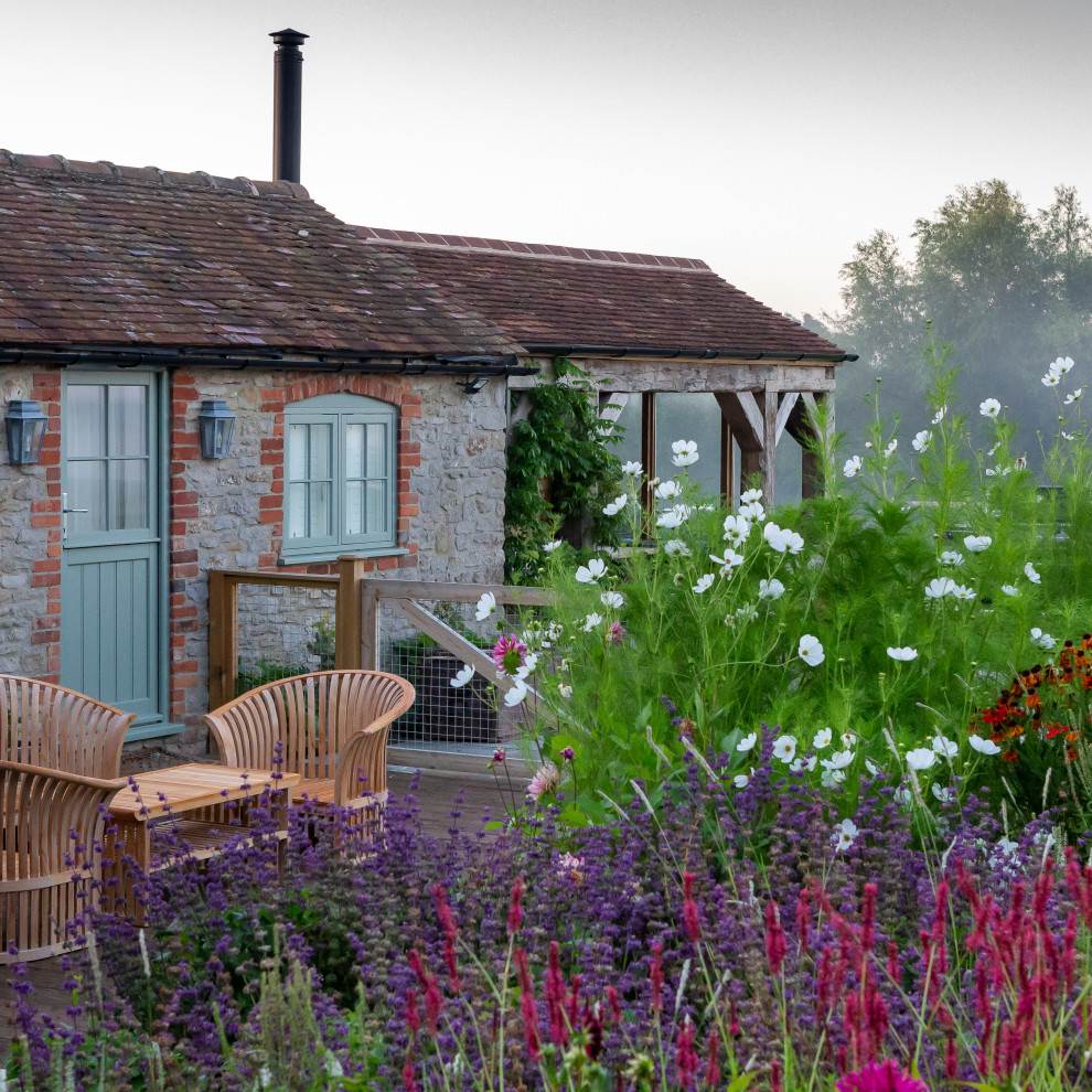 オックスフォードシャーにある高級な広い、夏のカントリー風のおしゃれな庭 (日向、天然石敷き、石フェンス) の写真