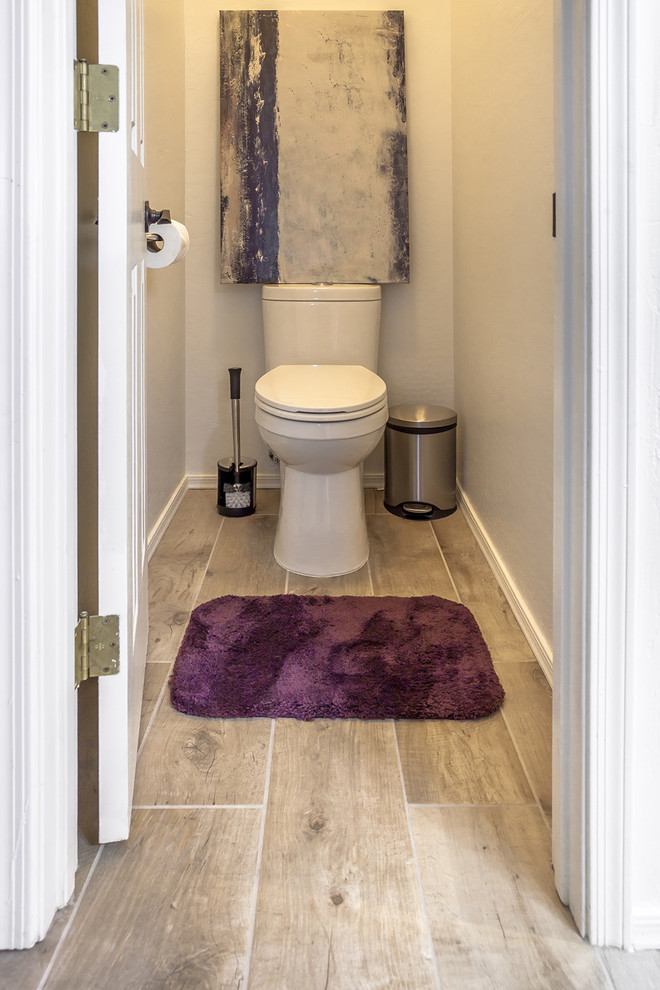 Inspiration for a mid-sized transitional powder room in Phoenix with recessed-panel cabinets, dark wood cabinets, a one-piece toilet, beige tile, porcelain tile, orange walls, porcelain floors, an undermount sink, granite benchtops and brown floor.