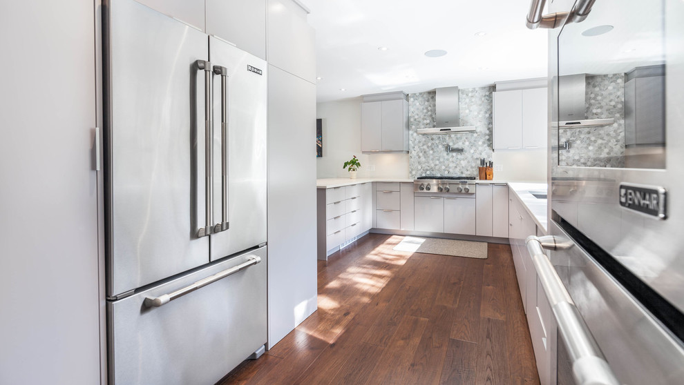 Inspiration for a large modern u-shaped dark wood floor and brown floor eat-in kitchen remodel with a double-bowl sink, flat-panel cabinets, gray cabinets, quartzite countertops, gray backsplash, stone tile backsplash, stainless steel appliances and a peninsula