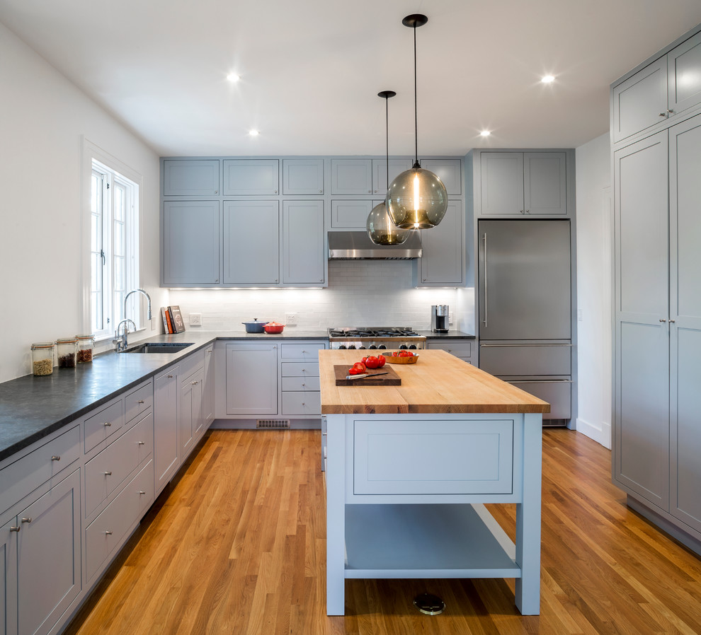This is an example of a transitional u-shaped kitchen in Bridgeport with an undermount sink, shaker cabinets, blue cabinets, white splashback, stainless steel appliances, medium hardwood floors and with island.